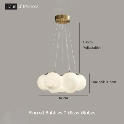 The Blurred Bubbles Chandelier by XCEPTION features seven frosted glass globes hanging from a gold-colored ceiling mount, with an adjustable height of 150cm and each globe having a diameter of 15cm.