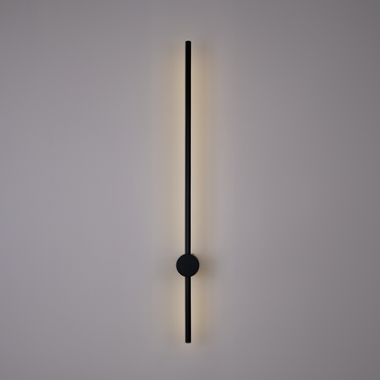 The Nordic Light Stick • 2-Pack by XCEPTION is a minimalist wall lamp with a vertical design, featuring a slim black rod and a circular center. It emits a soft, ambient light against a plain white background.