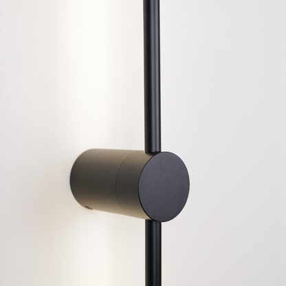 Close-up of the XCEPTION Nordic Light Stick, a modern, minimalist wall-mounted light fixture featured as part of a 2-pack set. It showcases a cylindrical base with a vertical rod in a black matte finish, beautifully mounted against a light-colored wall.