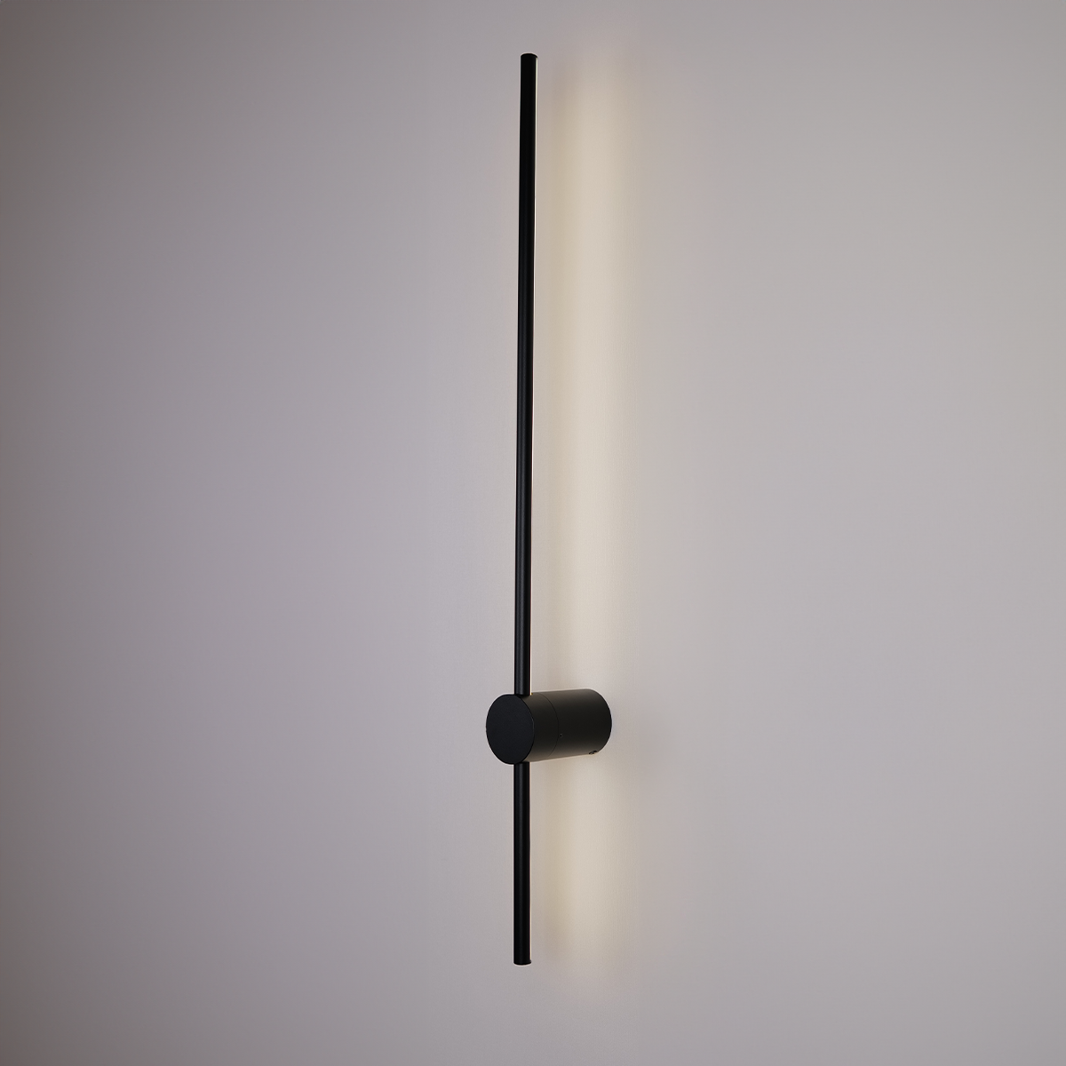 Introducing the Nordic Light Stick • 2-Pack from XCEPTION: a minimalist timepiece featuring a black cylindrical central hub and a long, slender hand poised vertically. The softly illuminated structure casts a subtle glow on the surrounding wall.