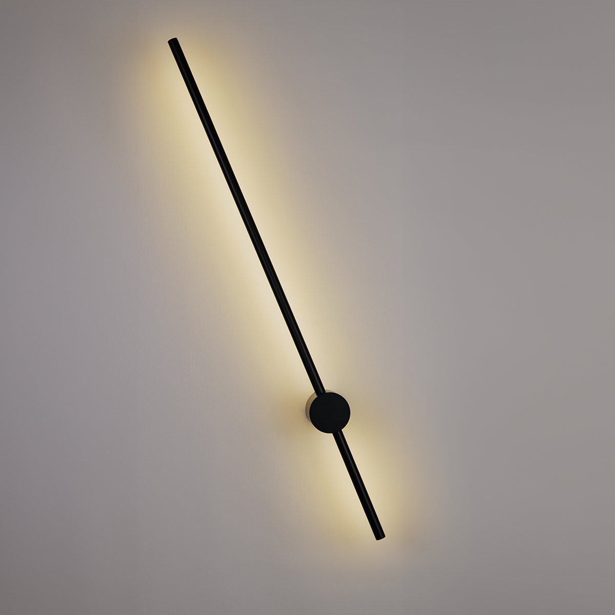The Nordic Light Stick • 2-Pack by XCEPTION features a minimalist design with a long, diagonal black rod that emits a soft yellow glow, beautifully contrasting against a gray background. The rod is centrally affixed by a circular base.