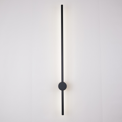 Introducing the Nordic Light Stick • 2-Pack by XCEPTION: a contemporary minimalist wall light design that showcases a vertical black rod mounted on a circular base. This elegant rod casts a gentle, even glow across the plain, off-white surface behind it.