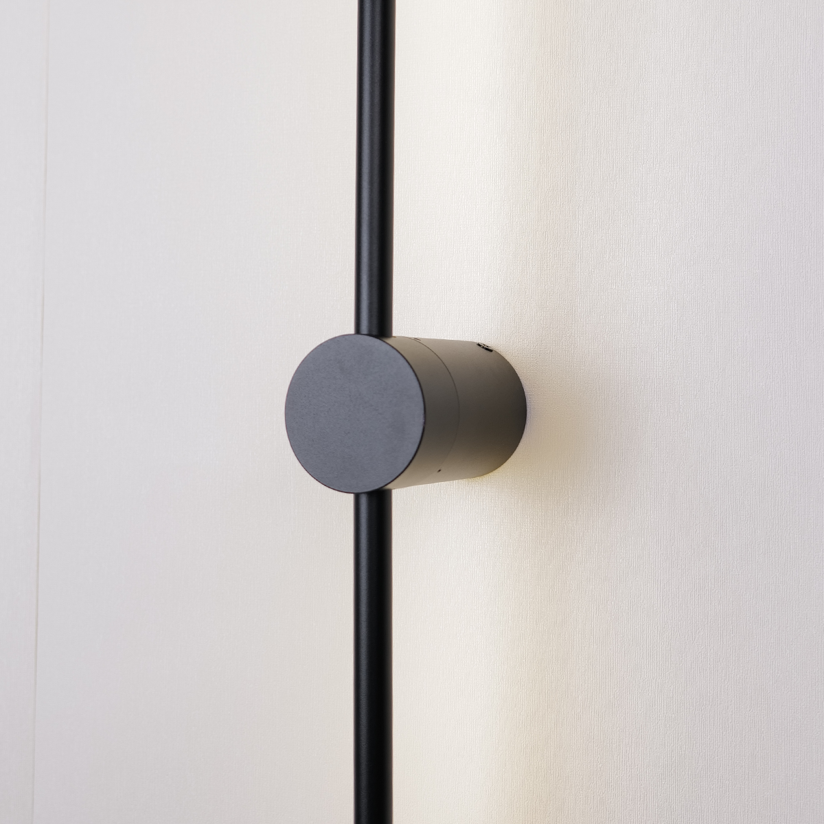 Close-up of the Nordic Light Stick by XCEPTION, featuring a sleek black cylindrical fixture mounted on a vertical rod against a light-colored wall, casting a soft glow—available as a 2-pack.