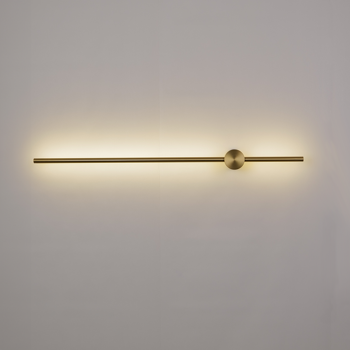Introducing the Nordic Light Stick • 2-Pack by XCEPTION, a minimalist wall sconce featuring a sleek, horizontal brass rod and a central sphere. Mounted on a white wall, it emits a warm, ambient glow.