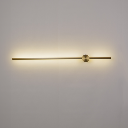 Introducing the Nordic Light Stick • 2-Pack by XCEPTION, a minimalist wall sconce featuring a sleek, horizontal brass rod and a central sphere. Mounted on a white wall, it emits a warm, ambient glow.