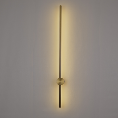 The Nordic Light Stick • 2-Pack by XCEPTION features a sleek, vertical wall light fixture with a long, slender metallic rod that casts a warm glow on a plain backdrop. A small sphere intersects the rod at the center, contributing to its simple yet sophisticated design.