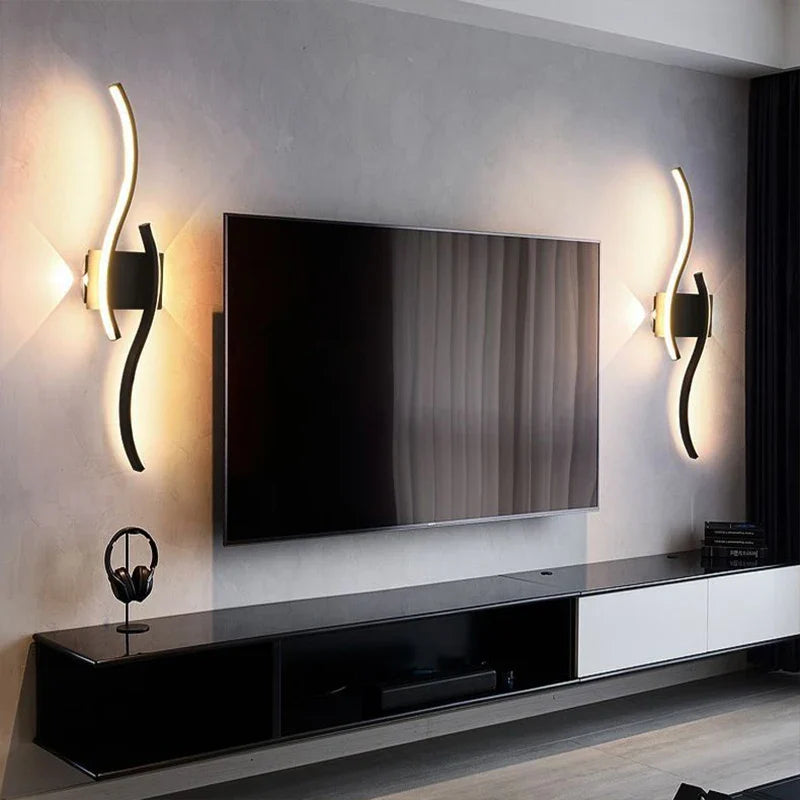 In a contemporary living room, a large flat-screen TV is mounted on the wall. On either side of the TV are Minimalisto Wall lights by XCEPTION, casting a cozy glow. Beneath the TV sits a sleek black and white media console equipped with intelligent control features, with a pair of headphones hanging on one side.