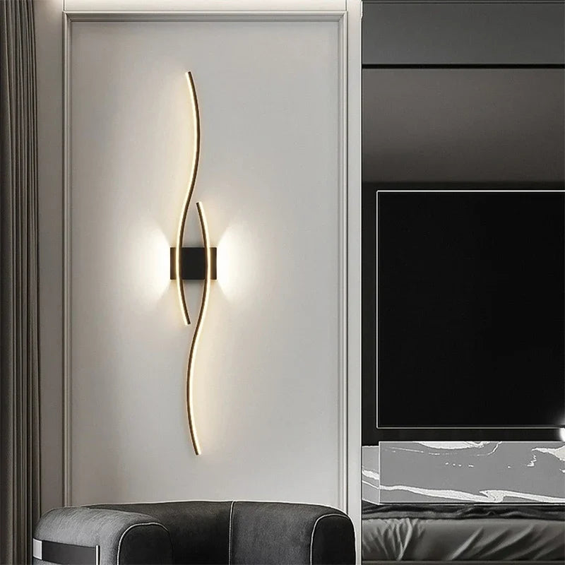 In the modern living room, a stylish black armchair complements the large flat-screen TV mounted on the wall. Intelligent control of XCEPTION's Minimalisto Wall Light adds efficiency, while a unique wavy light fixture illuminates the adjacent wall, enhancing the contemporary charm of the decor.