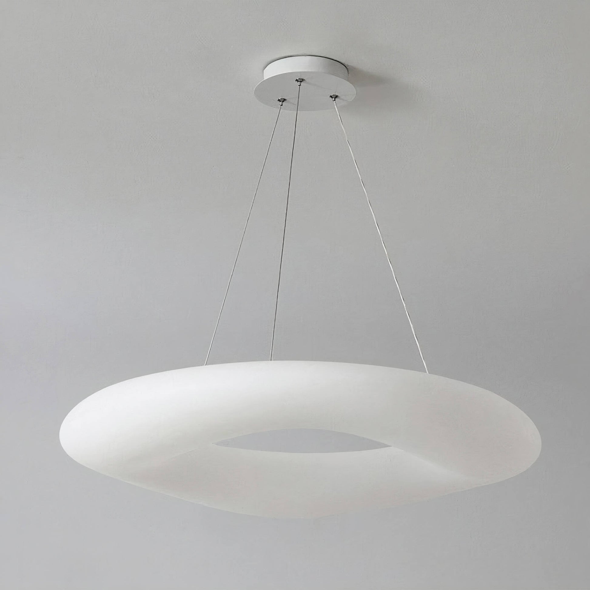 The Cloud Ceiling Light by XCEPTION is a contemporary white, doughnut-shaped pendant fixture hung from the ceiling with three slender wires, offering a minimalist and elegant appearance against a simple gray background.