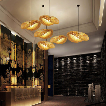 A luxurious hotel lobby showcases six elegant, bamboo pendant lights from XCEPTION hanging gracefully from the high ceiling. The walls are adorned with ornate traditional art and are beautifully complemented by a Southeast Asian style stone wall softly illuminated on the right.