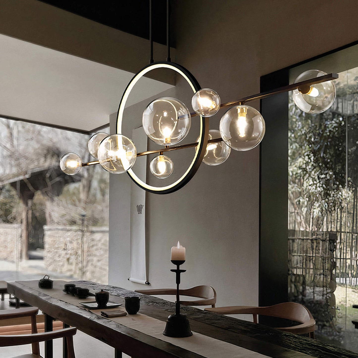 A modern dining room showcasing the Comos Ceiling Light by XCEPTION, featuring a large, contemporary design with spherical glass bulbs. The room includes a long wooden table adorned with a lit candle centerpiece, surrounded by wooden chairs. In the background, expansive windows provide a view of the garden.